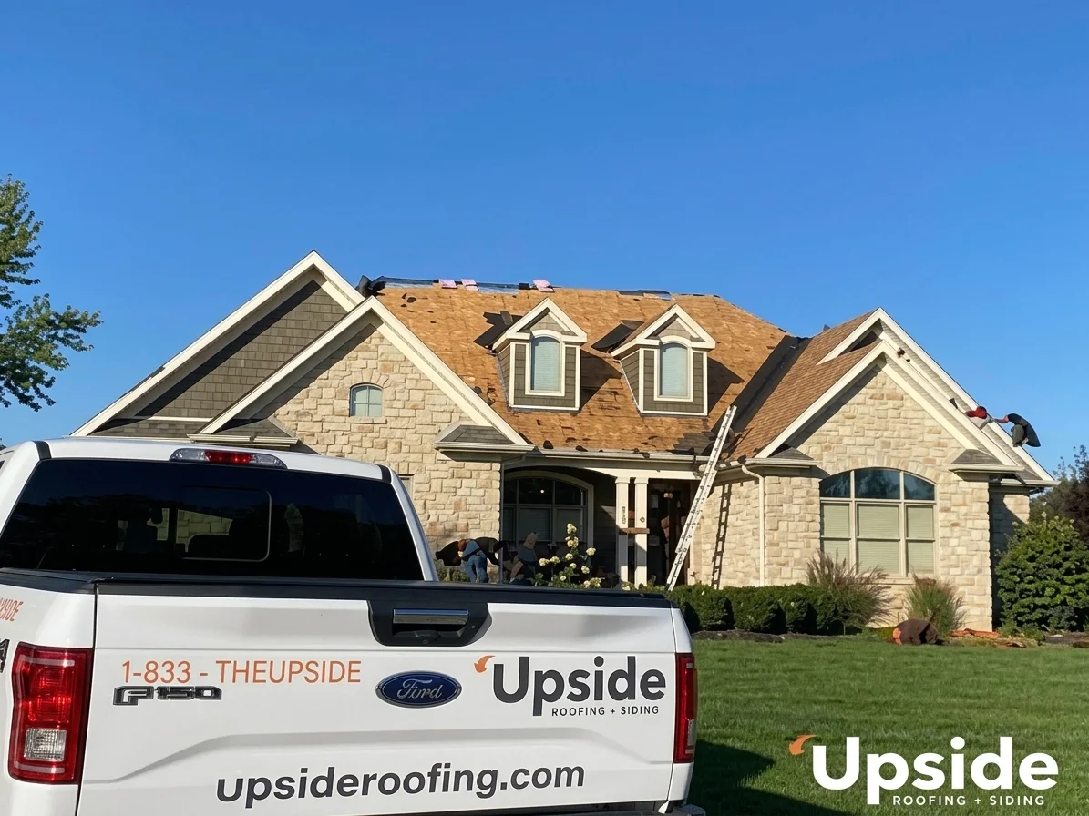 Upside Roofing & Siding crew working on a stone home with the Upside truck in the foreground